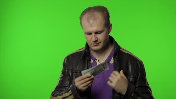 Rocker man werknemer neemt geld dollar contant bankbiljetten uit zijn zak en biedt ze aan de camera — Stockvideo