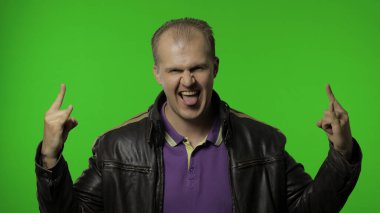 Rock 'n roll işareti gösteren rockçı adam, şeytan boynuzu hareketi, çılgın bir ifadeyle bakıyor.