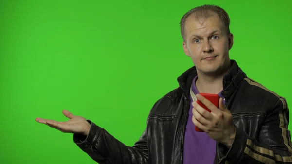 Rocker man showing side advertising area. Using smartphone, pointing at wall for your text, logo — Stock Photo, Image