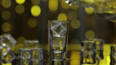 Barmen şişeden shot bardağına donmuş votka döktü. Pırıl pırıl altın parti geçmişine karşı buz küpleri