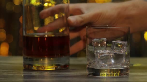 Häll gyllene whisky, konjak eller konjak från flaskan i glas med isbitar. Glänsande bakgrund — Stockvideo
