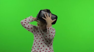 Çocuk kız oyun oynamak için kulaklık kullanıyor. Sanal gerçeklik 3D 360 videosunu izliyorum. Krom anahtar