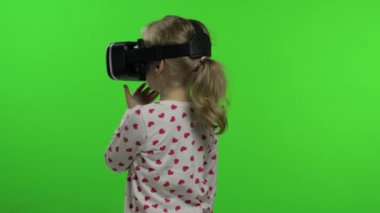 Çocuk kız oyun oynamak için kulaklık kullanıyor. Sanal gerçeklik 3D 360 videosunu izliyorum. Krom anahtar