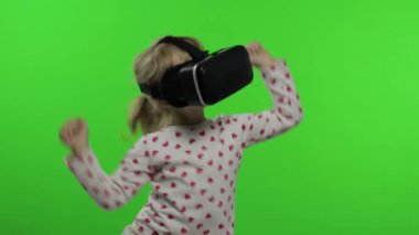 Çocuk kız oyun oynamak için kulaklık kullanıyor. Sanal gerçeklik 3D 360 videosunu izliyorum. Dans etmek.