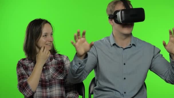 Man en vrouw met behulp van VR-headset helm om spel te spelen. Het bekijken van virtual reality 3D video. Chromatoetsen — Stockvideo