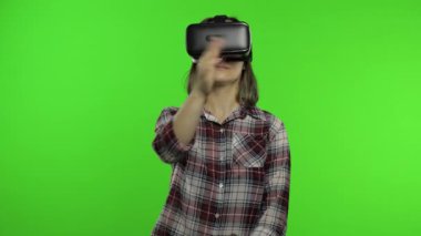 Simülasyon oyunu oynamak için VR uygulama kaskı kullanan kız. Jestler kayıyor. Sanal gerçeklik 3D video izliyor