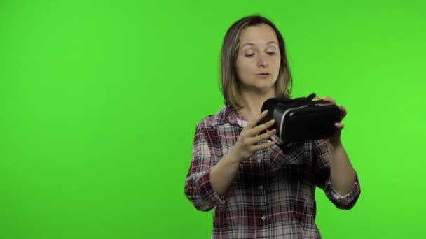 Nuori nainen käyttää VR kuulokkeiden kypärä pelata peliä, osoittaa puolella mainonta alue. Kroma-avain — kuvapankkivideo