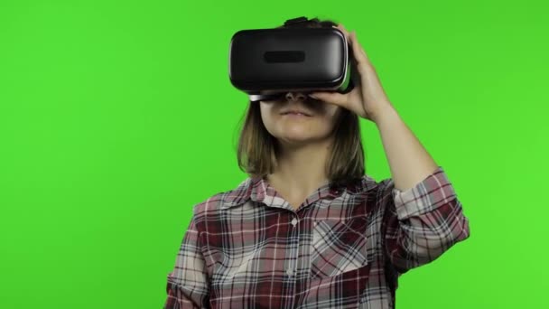 Девушка, использующая VR шлем приложения, чтобы играть в симуляционную игру. Слайд-жест. Просмотр 3D видео виртуальной реальности — стоковое видео