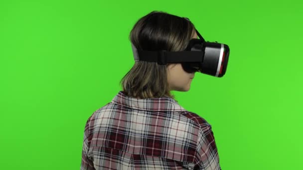 Młoda dziewczyna używająca kasku VR do gry symulacyjnej. Kobieta ogląda wirtualną rzeczywistość wideo 3D — Wideo stockowe