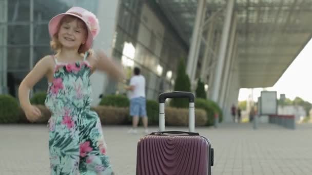 Touristin mit Koffer in der Nähe des Flughafens. Kind tanzt, jubelt, feiert — Stockvideo