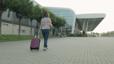 İş kadını bir gezgin bavulla havaalanına doğru yürüyor. Kız valizi yürütür ve yuvarlar. Turizm