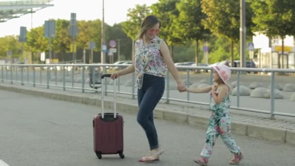 Mother and daughter walking outdoors to airport. Woman carrying suitcase bag. Child and mom vacation — Stock Video