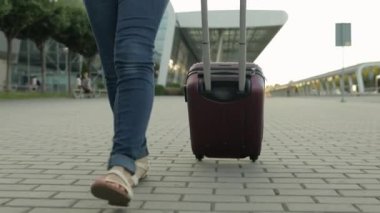İş kadını turistlerin bacakları bavullarla yürüyor. Tekerlekli bavulla sokakta yürü.
