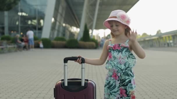 Παιδί κορίτσι τουρίστρια με βαλίτσα κοντά στο αεροδρόμιο. Παιδικό χέρι, περπατά στο δρόμο με τσάντα. Διακοπές — Αρχείο Βίντεο