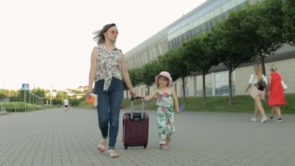 Мать и дочь идут на улицу в аэропорт. Женщина с чемоданом. Отдых для детей и мамы — стоковое видео