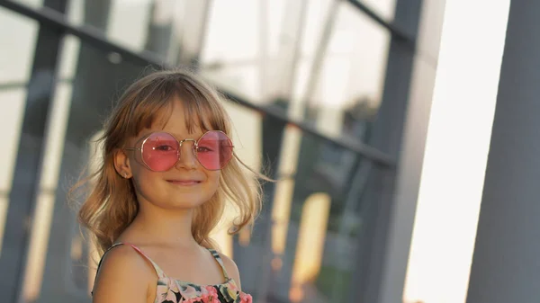 Miúda ao pôr do sol a usar óculos de sol no aeroporto. Criança turística. Olhar estilo havaiano. Férias — Fotografia de Stock