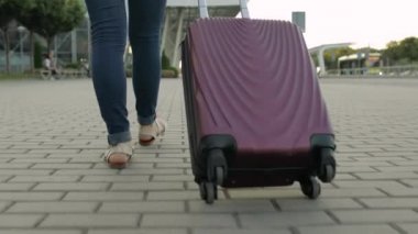 İş kadını turist bavulla yürüyor. Tekerlekli bavulla sokakta yürü.