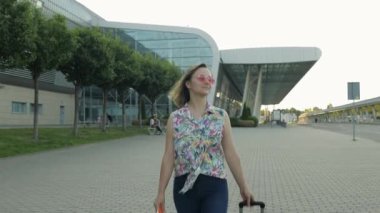 Havaalanından bavulla gelen bir kadın turist. Kız durur ve gülümsemeye başlar, sevinir. Tatil