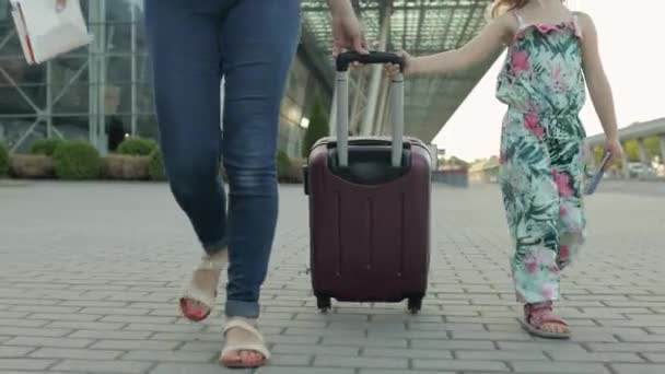 母親と娘が空港から歩いている。スーツケースバッグを持ってる女性。休暇後の子供とお母さん — ストック動画