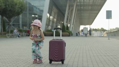 Havaalanı yakınlarında çanta taşıyan bir çocuk turist. Küçük çocuk dans ediyor, zıplıyor, bavulla kutluyor.