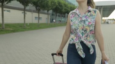 İş kadını turist bavulla yürüyor. Bavul ve biletlerle sokakta yürü.
