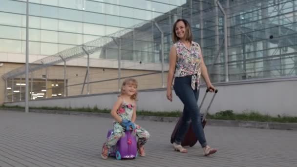 Moeder, dochter loopt van het vliegveld na vakantie. Een vrouw met bagage. Reiskoffer voor kinderen — Stockvideo