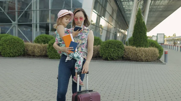 Moeder en dochter in de buurt van vliegveld. Vrouw houdt paspoorten en tickets bij de hand. Kind en moeder vakantie — Stockfoto