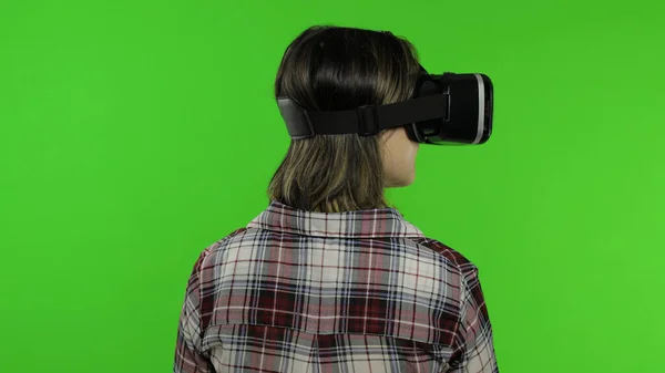 Chica joven usando casco de aplicación VR para jugar juego de simulación. Mujer viendo realidad virtual 3d video —  Fotos de Stock
