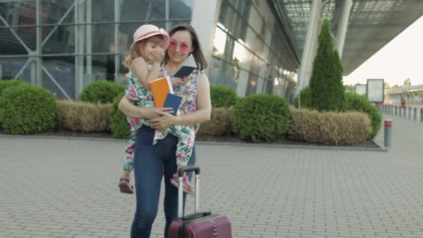 Mãe e filha perto do aeroporto. Mulher segurar passaportes e bilhetes na mão. Criança e mãe férias — Vídeo de Stock