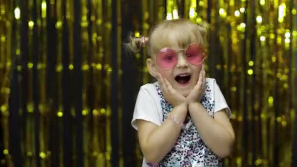 Danse d'enfant, spectacle stupéfiant, plaisanterie, sourire. Fille posant sur le fond avec rideau de papier d'aluminium — Video