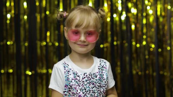 Child show ok sign, smiling, looking at camera. Girl posing on background with foil golden curtain — Stock Video