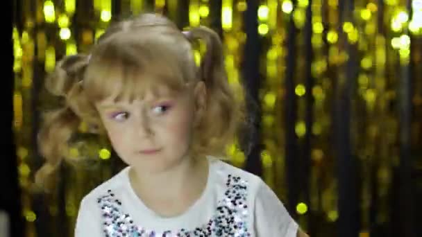 Stylish child dancing fooling around, make faces. Girl posing on background with foil golden curtain — Stock Video