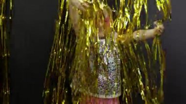 Mutlu çocuk dansları, oyunlar, parlak folyoyla süslenmiş altın perdelerde oynaşmalar. Küçük sarışın çocuk.