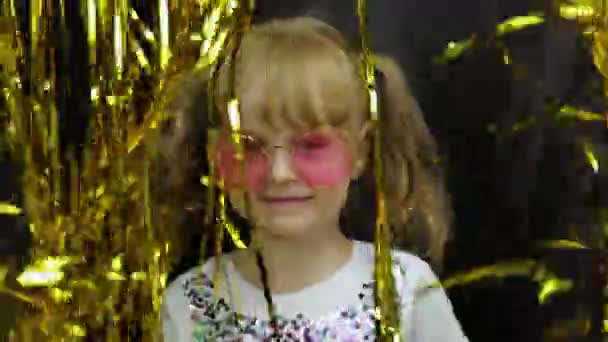 Joyeux enfant sautant, jouant, s'amusant dans le rideau doré frange feuille brillante. Petite fille blonde — Video