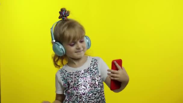 Balli per bambini con smartphone, ascolto di musica con le cuffie. La bambina che balla, avendo hun — Video Stock