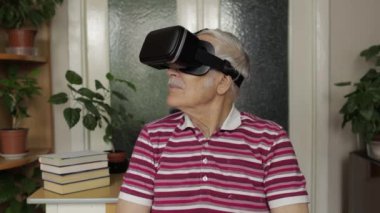 Sanal gözlüklü büyük baba evde 360 VR kasklı 3D video izliyor.