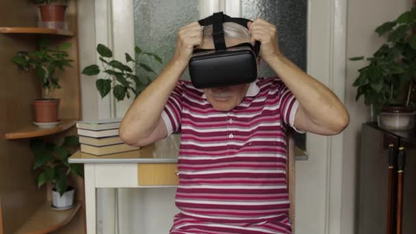 Ανώτερος παππούς βάζοντας εικονικά ακουστικά γυαλιά και βλέποντας 3D βίντεο σε 360 VR κράνος στο σπίτι — Αρχείο Βίντεο