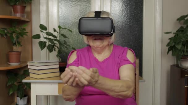 Senior mormor kvinna i virtuella headset glasögon titta på 3D-video i 360 vr hjälm hemma — Stockvideo