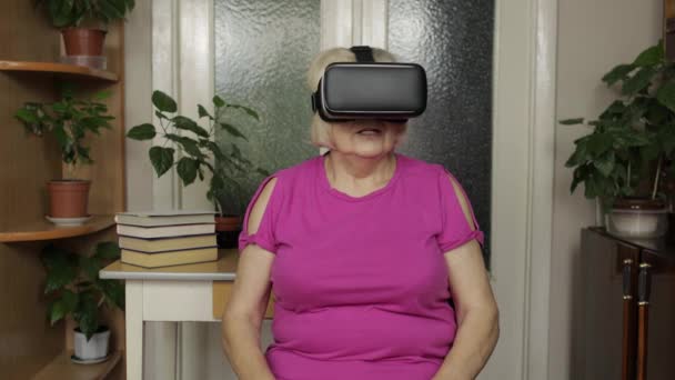 Испуганная бабушка женщина снимает очки виртуальной реальности, играя в страшные игры, показывает эмоции неожиданности — стоковое видео