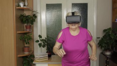 Sanal gözlüklü büyük anne VR kasklı 3D video izliyor ve evde koşuyor.