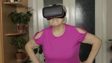 Sanal gözlüklü yaşlı büyükanne kadın evde 360 VR kaskla 3D video izliyor.