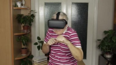 Sanal gözlüklü büyükanne, video kasklı eğitim kutusunda video izlerken yumruk yumruğa dövüşü gösteriyor.