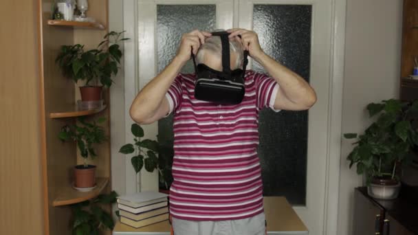 Starszy dziadek zakładający wirtualne okulary i oglądający wideo 3D w kasku 360 vr w domu — Wideo stockowe