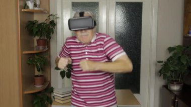 Sanal gözlüklü büyük baba 3 boyutlu kaskla video izleyip dans ediyor, eğleniyor.