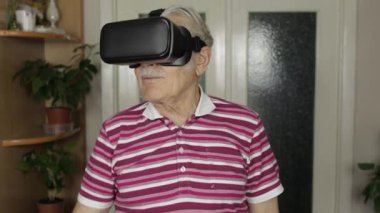 Sanal gözlüklü büyük baba evde 360 VR kasklı 3D video izliyor.