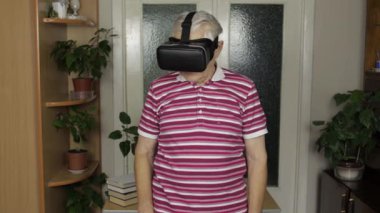Sanal gözlüklü büyük baba evde 360 VR kasklı 3D video izliyor.
