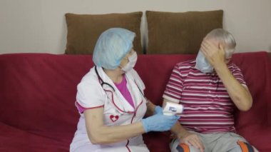 Hemşire, hasta büyükbabanın elektriksel termometresiyle ısıyı ölçüyor. Coronavirüs