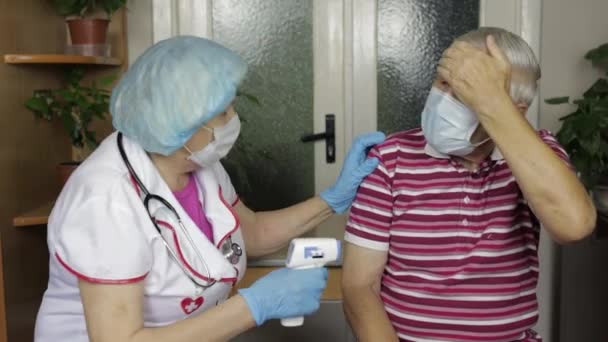 Enfermeira mede a temperatura com termômetro eletrônico sem contato do avô doente. Coronavírus — Vídeo de Stock