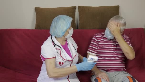 Enfermeira mede a temperatura com termômetro eletrônico sem contato do avô doente. Coronavírus — Vídeo de Stock