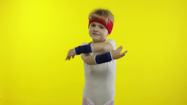 Happy cute girl w białej odzieży sportowej pokazując kciuki w górę gest izolowany na żółtym tle. Sprawność — Wideo stockowe